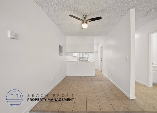 A spacious room with a ceiling fan and tiled floor.
