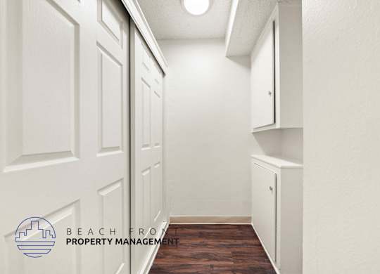 A hallway with white doors and a logo for Beachfront Property Management.