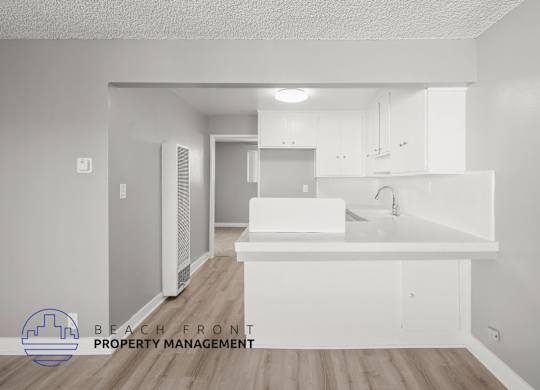 A white kitchen with a logo for Beach Front Property Management.
