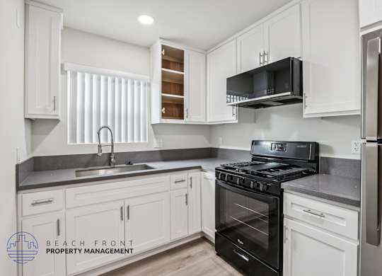 A kitchen with white cabinets and black appliances.