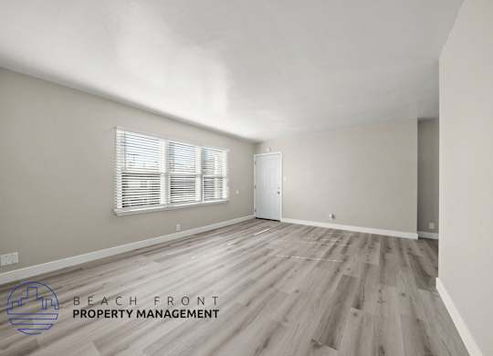 A room with wooden flooring and a window with blinds.