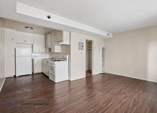A kitchen with white appliances and wooden floors.