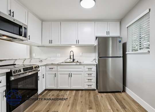 A modern kitchen with white cabinets and stainless steel appliances.