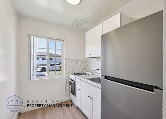 A kitchen with a stainless steel refrigerator and white cabinets.