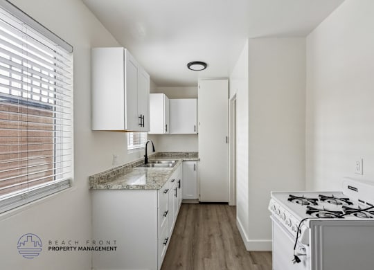 A kitchen with white cabinets and a white stove top oven.