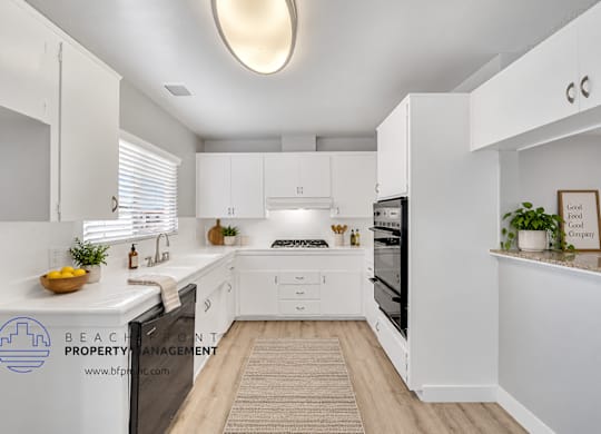 A clean, white kitchen with a skylight and a fridge on the left.