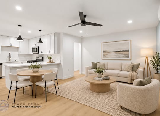 A well-lit, modern living room with a dining area and kitchen in the background.