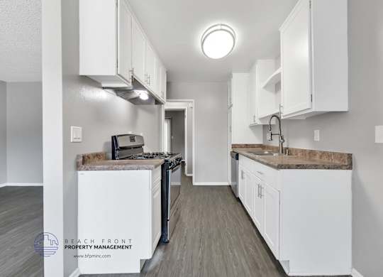 A kitchen with white cabinets and a wooden floor.