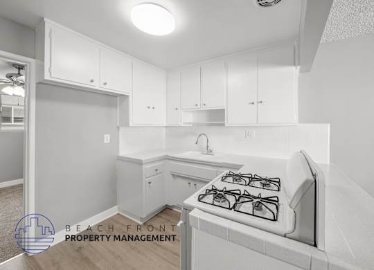 A kitchen with a stove top oven and cabinets.