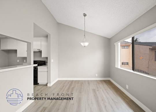 an empty living room and kitchen with wood flooring and a window