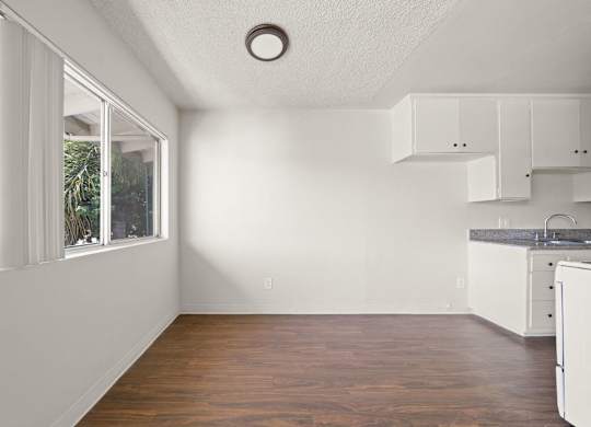 A kitchen with white cabinets and a window.