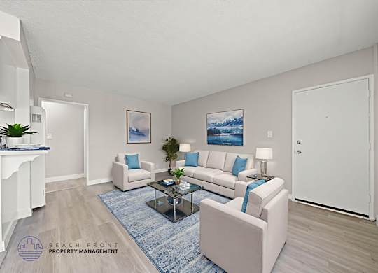 A living room with a white couch, a blue rug, and a painting on the wall.