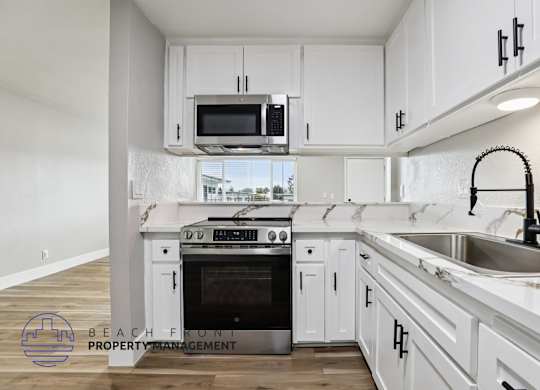 A kitchen with white cabinets and a black faucet.