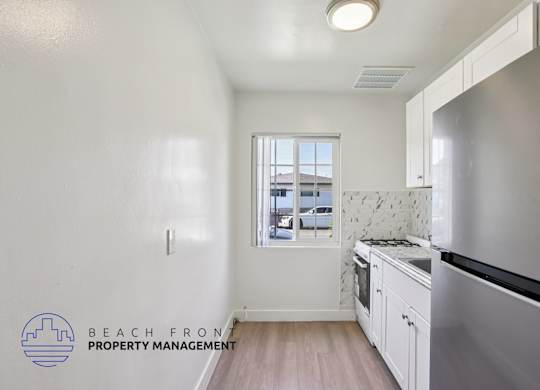 A kitchen with a stainless steel refrigerator and wooden floors.