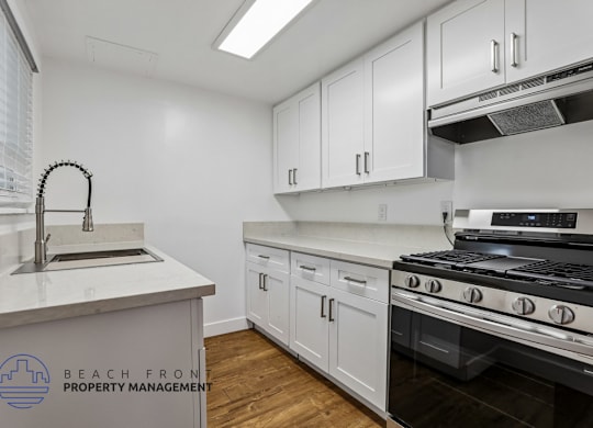 A kitchen with white cabinets and a stove top oven.