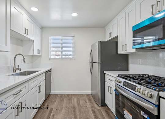 A kitchen with white cabinets and a black refrigerator.