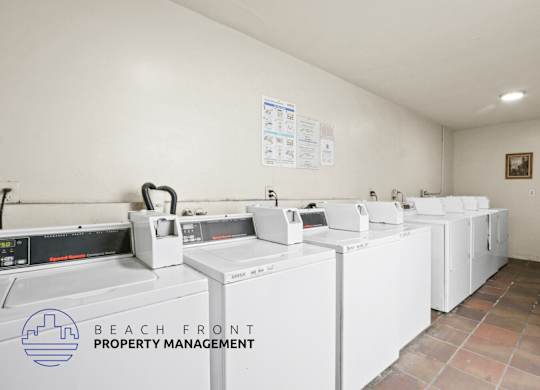 A laundry room with washers and dryers and a sign that says Beach Front Property Management.