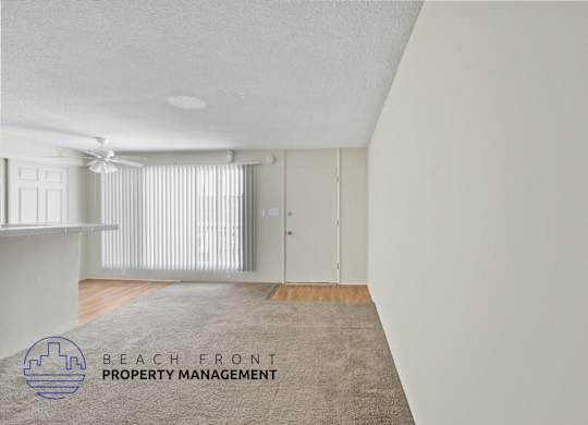 A room with a carpet on the floor and a logo for Beach Front Property Management in the corner.
