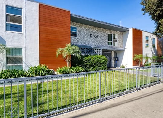 A modern building with a grey and orange facade and a metal fence in front.