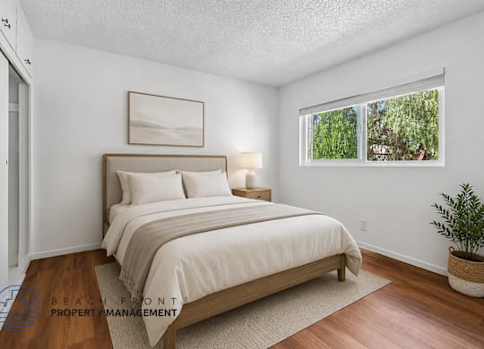 A bedroom with a large bed and a window overlooking a green area.