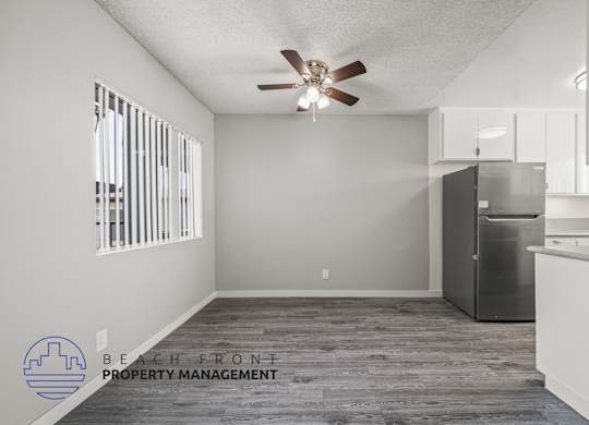 A spacious kitchen and living room with a ceiling fan and wooden flooring.