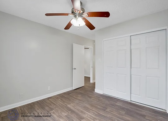 A room with a ceiling fan and a white door.