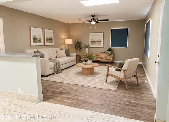A living room with a white couch, a wooden coffee table, and a ceiling fan.