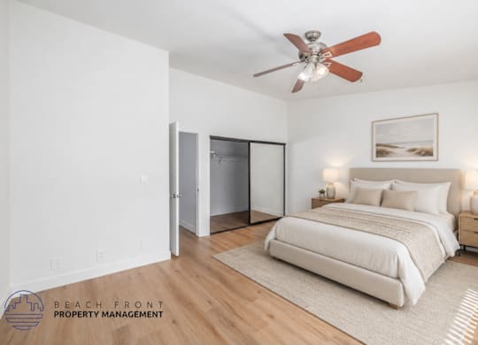 A bedroom with a bed, a ceiling fan, and a nightstand with a lamp.