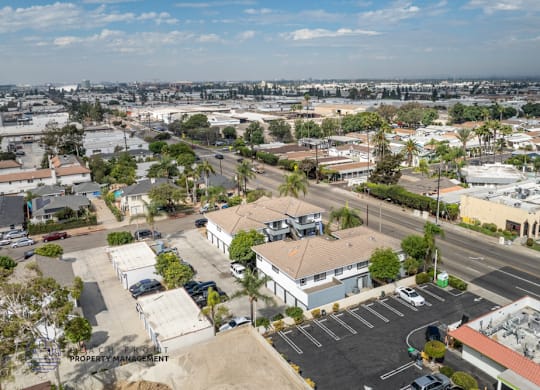 A parking lot with a building in the background and a tree in the foreground.