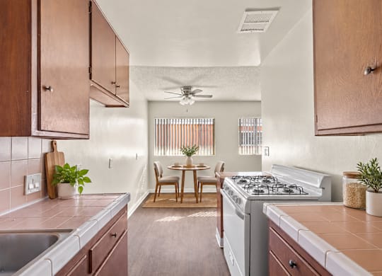 A kitchen with a stove, sink, and dining table.