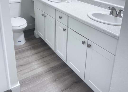 A white bathroom with a toilet, sink, and mirror.