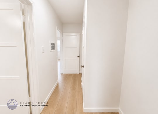 A hallway with white walls and wooden flooring.
