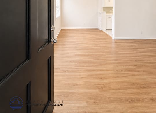 A room with a black door and wooden flooring.