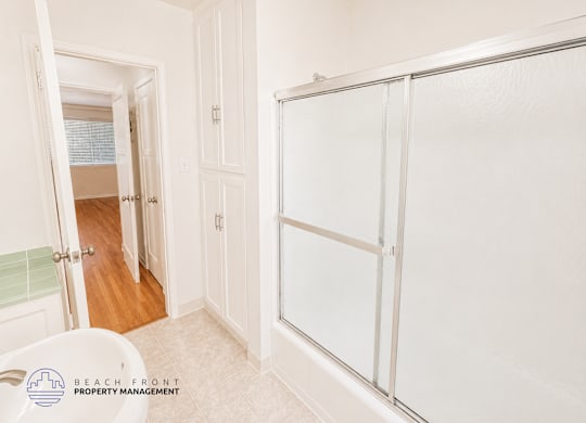 A white bathroom with a walk in shower and a toilet.