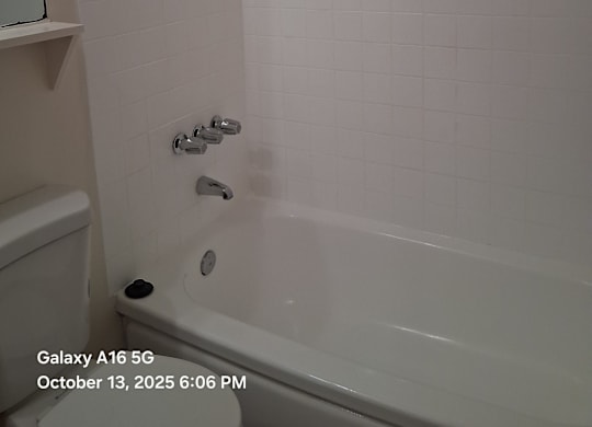 A white tiled bathroom with a shower and a toilet.