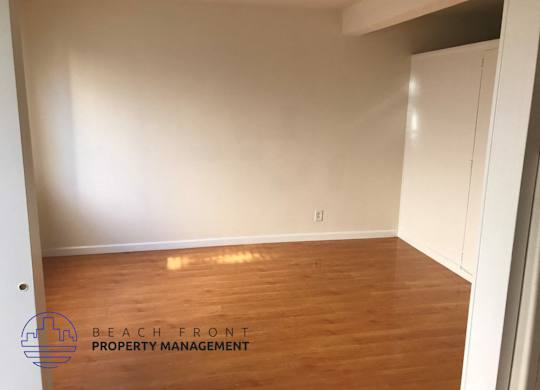 an empty room with wood flooring and white walls