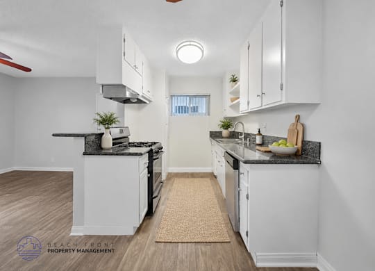 A kitchen with white cabinets and a black countertop.