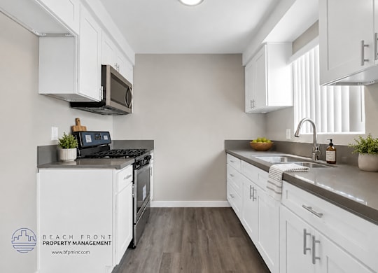 A kitchen with white cabinets and a black stove top.