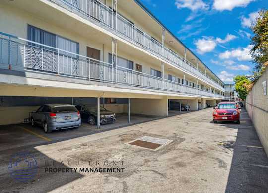 A parking lot with cars and a building with balconies in the background.