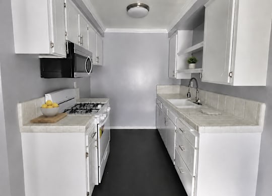A small white kitchen with a microwave, oven, and sink.