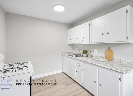 A kitchen with white cabinets and a marble countertop.