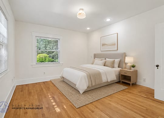 A bedroom with a large bed and a window overlooking a green area.