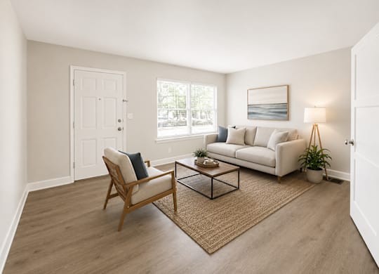 A living room with a white couch, a wooden chair, and a coffee table.