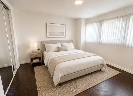 A bedroom with a large bed and a nightstand with a lamp.