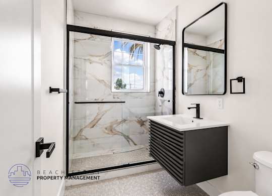 A bathroom with a marble sink and a glass shower door.