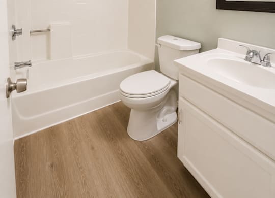 A white bathroom with a toilet, sink, and bathtub.