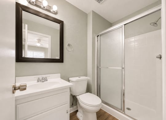 A white bathroom with a toilet, sink, and shower.