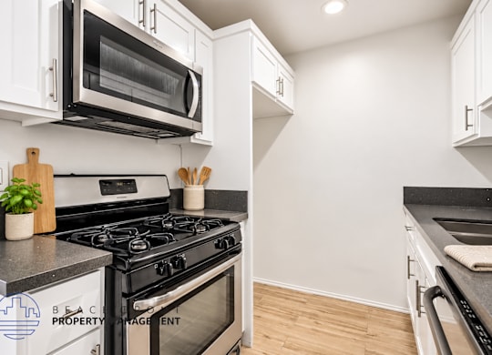 A modern kitchen with a black stove top oven and white cabinets.