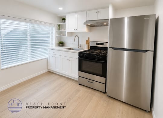 A modern kitchen with a stainless steel refrigerator and wooden flooring.