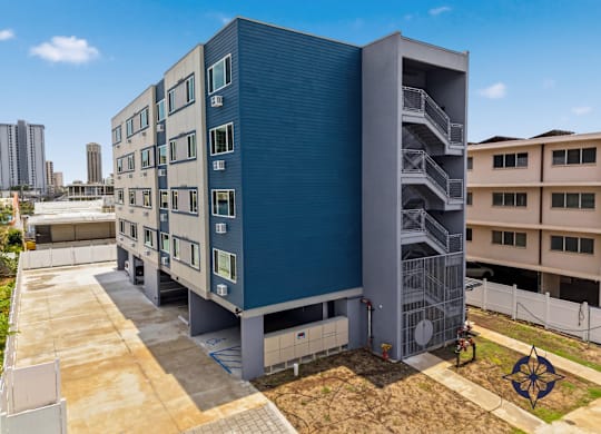 A modern building with a blue exterior and a parking lot in front.